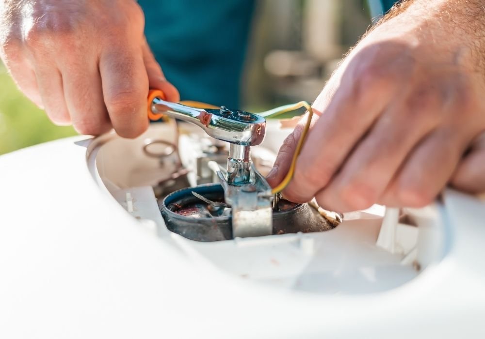 Close-up of a technician's hands using a socket wrench to tighten internal components during a cooling maintenance tune-up.